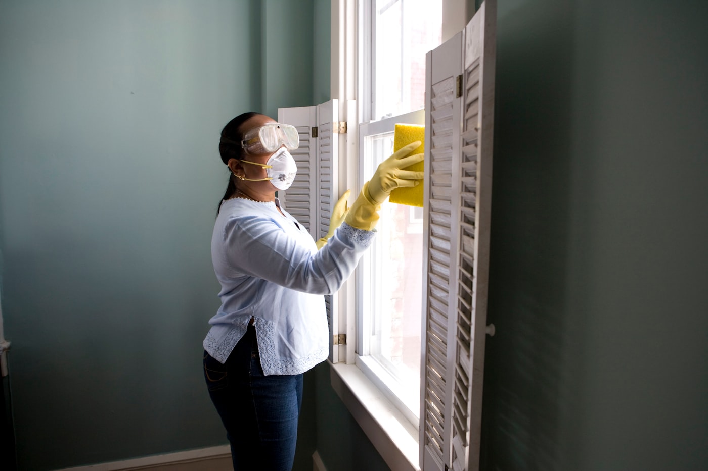 A cleaner detailing a window frame with a sponge